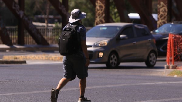 Persona caminando bajo el sol en la calle.