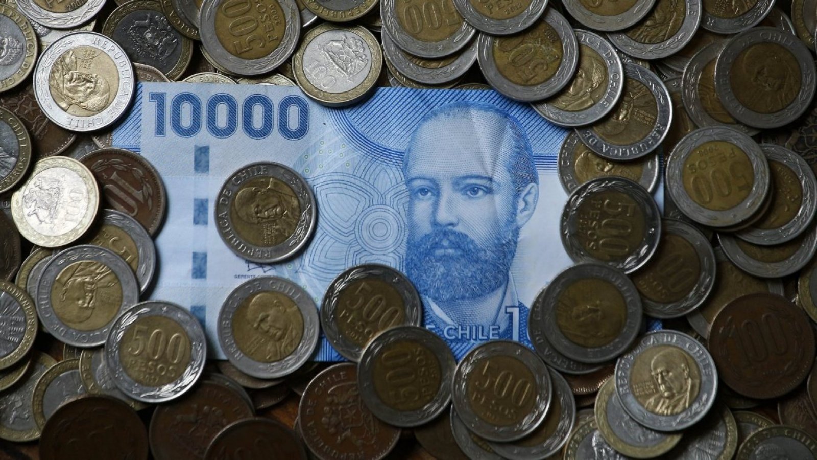Billete azul de 10 mil en medio de monedas de quinientos pesos.