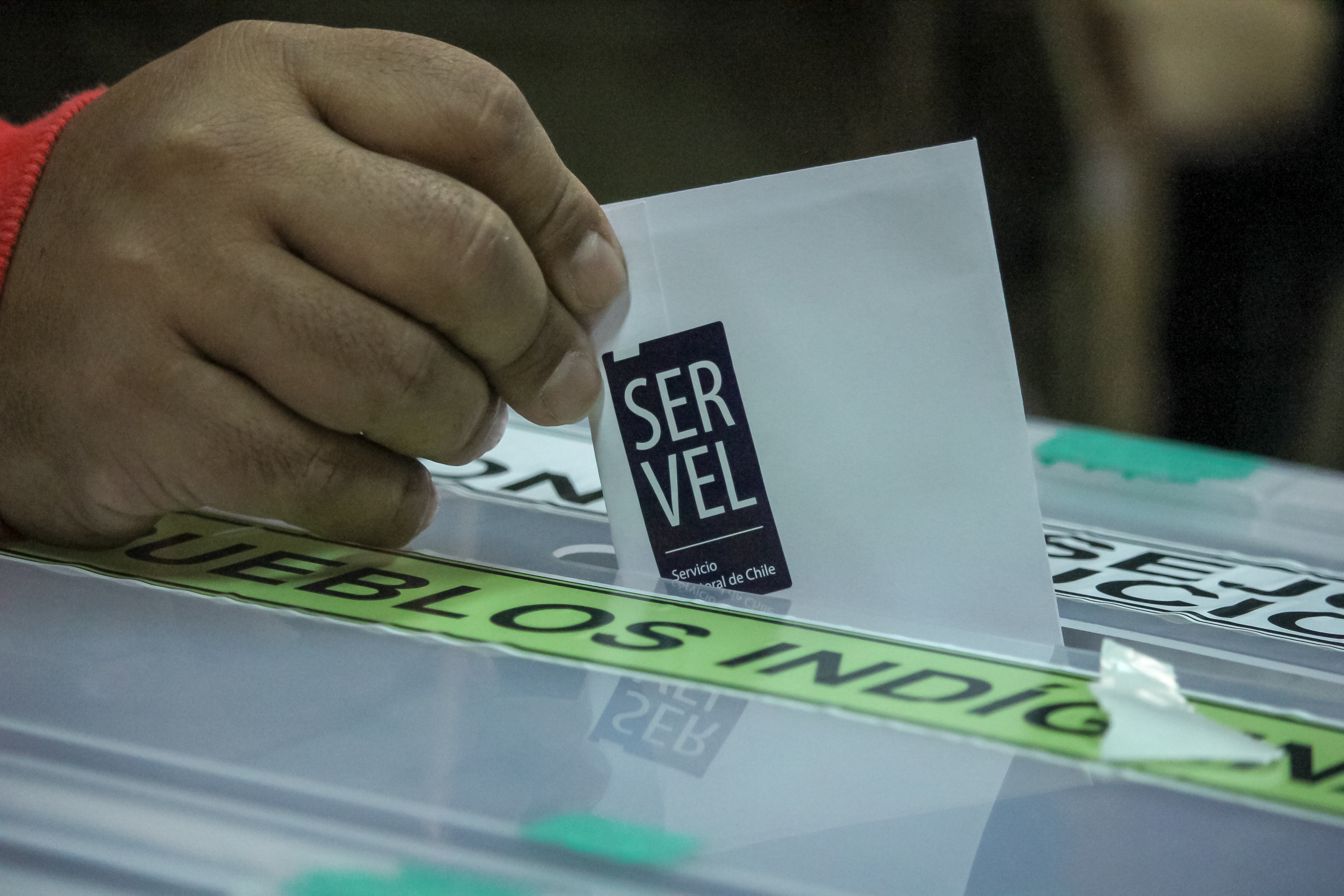 Voto con sticker del Servel ingresando a urna.