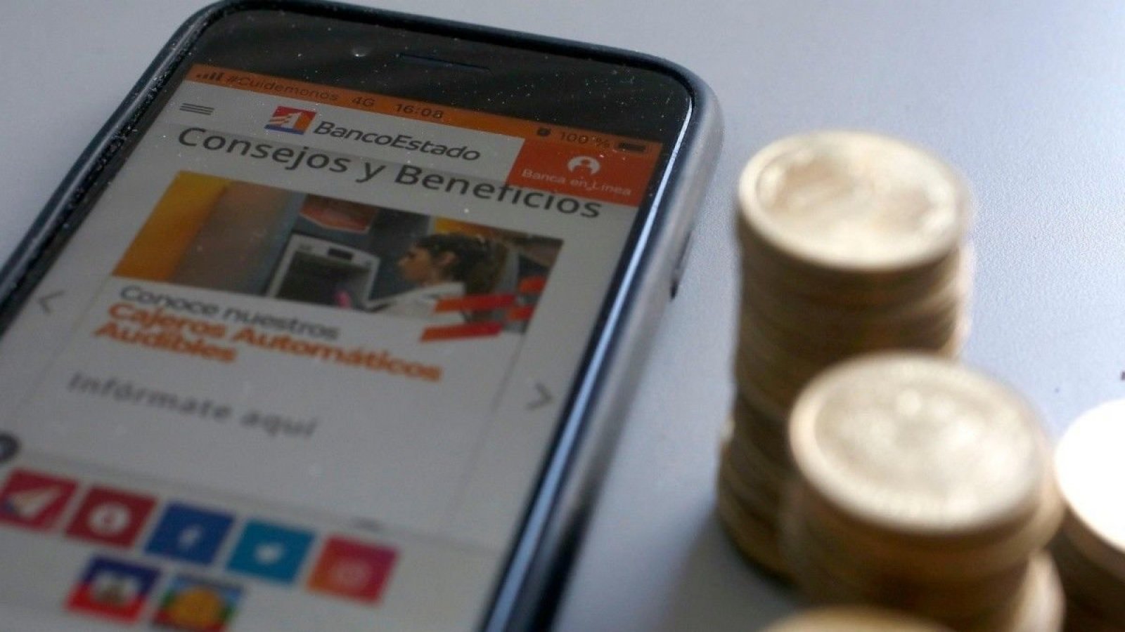 Celular y pantalla con pestaña abierta de la web del BancoEstado