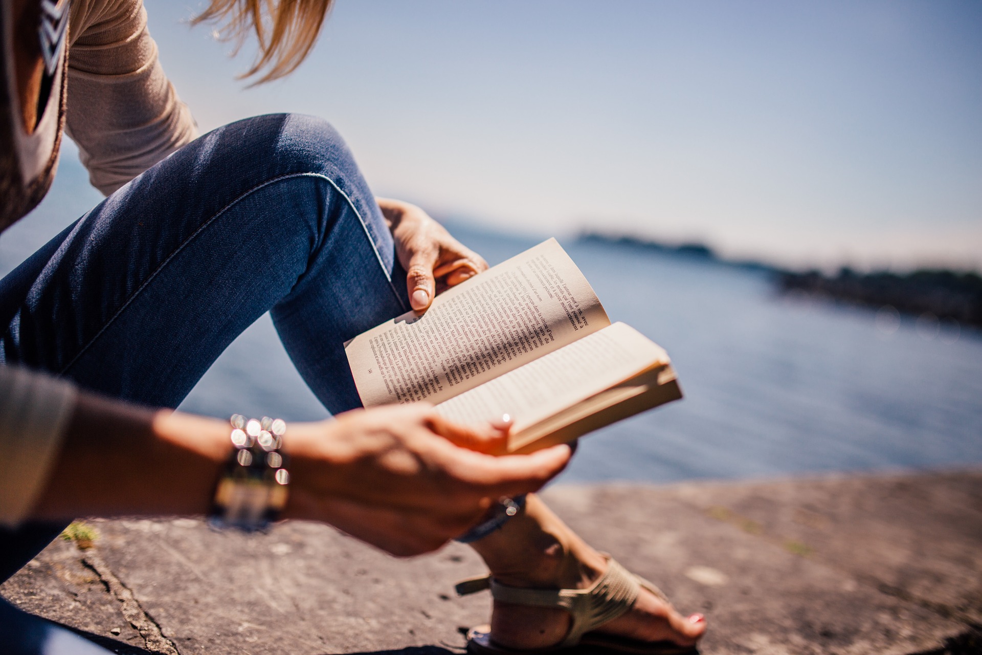 Mujer leyendo libro en la playa.