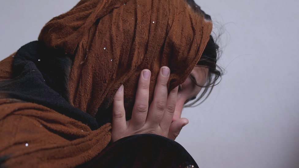 Una mujer afgana se seca las lágrimas de los ojos.