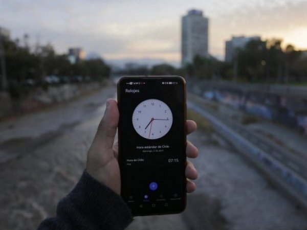 Persona con el reloj en un celular en la mano. Hora oficial.