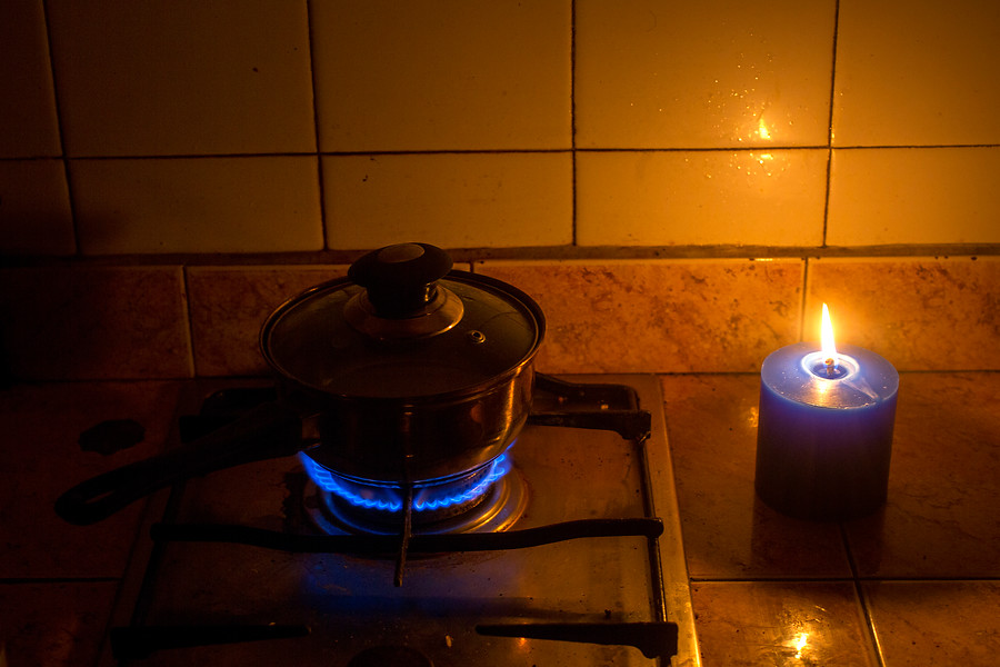 Olla encendida en un gas con una vela tras corte de luz