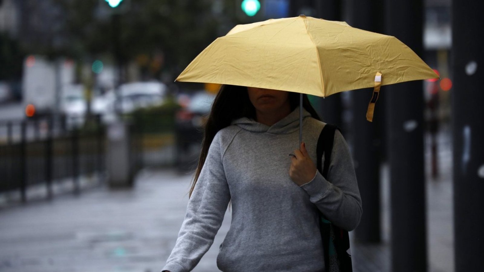Mujer con paragua amarillo caminando bajo la lluvia.