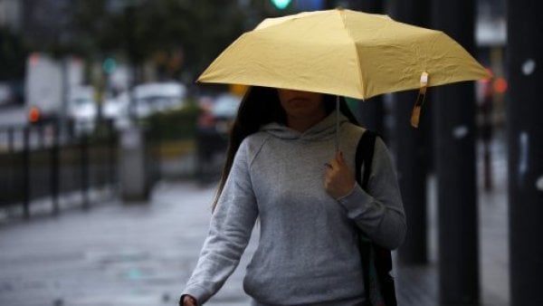 Mujer con paragua amarillo caminando bajo la lluvia.