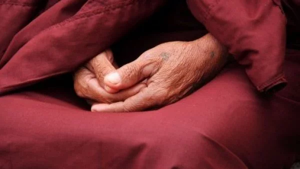 Manos juntas encima de una túnica de monje.