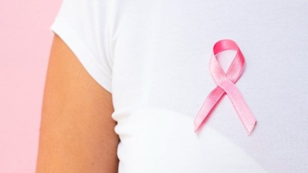 Mujer con un lazo rosado simbolizando la lucha contra el cáncer de mama.