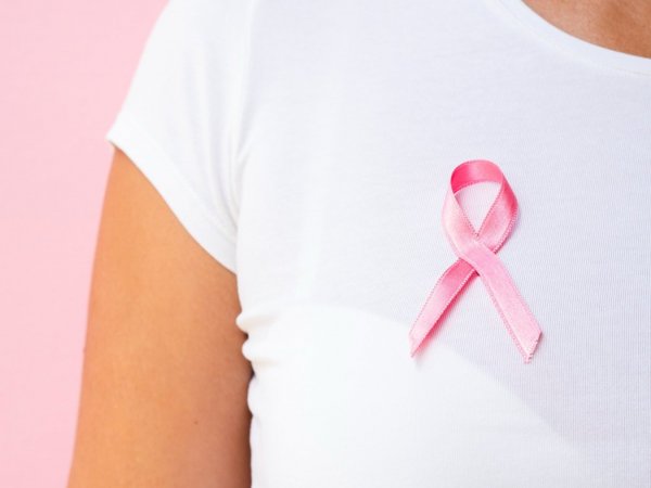 Mujer con un lazo rosado simbolizando la lucha contra el cáncer de mama.