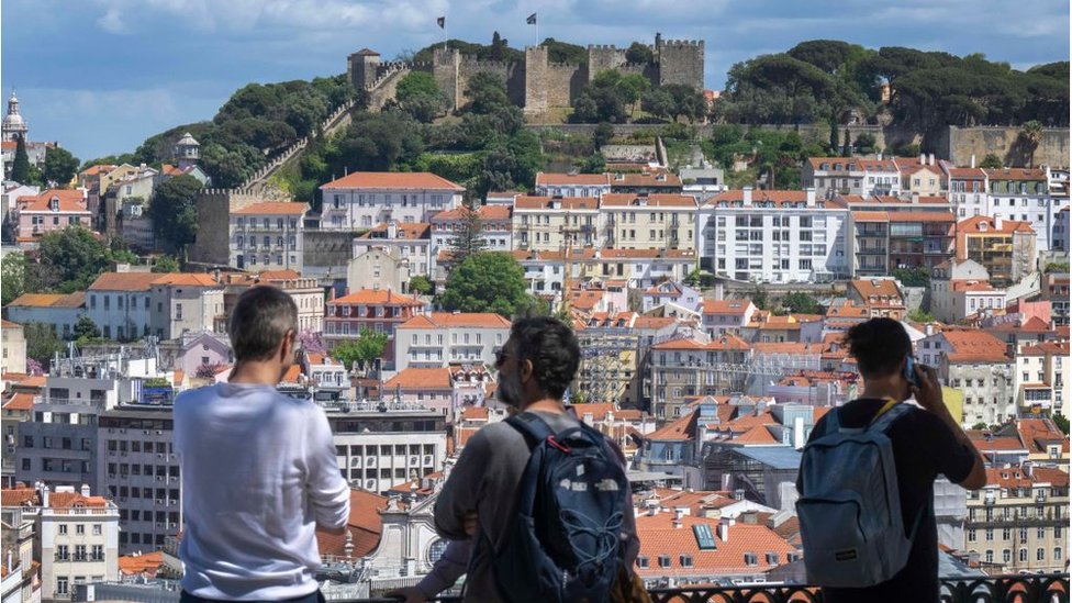 Unos turistas admirando la ciudad de Lisboa desde una colina.