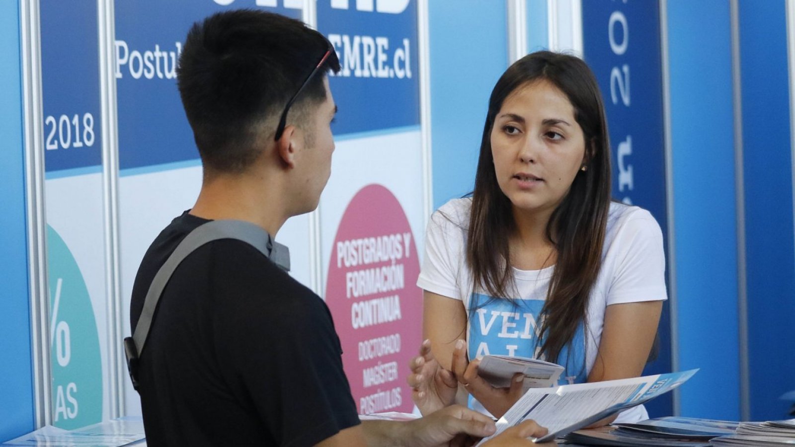 Estudiantes en feria universitaria conversando.