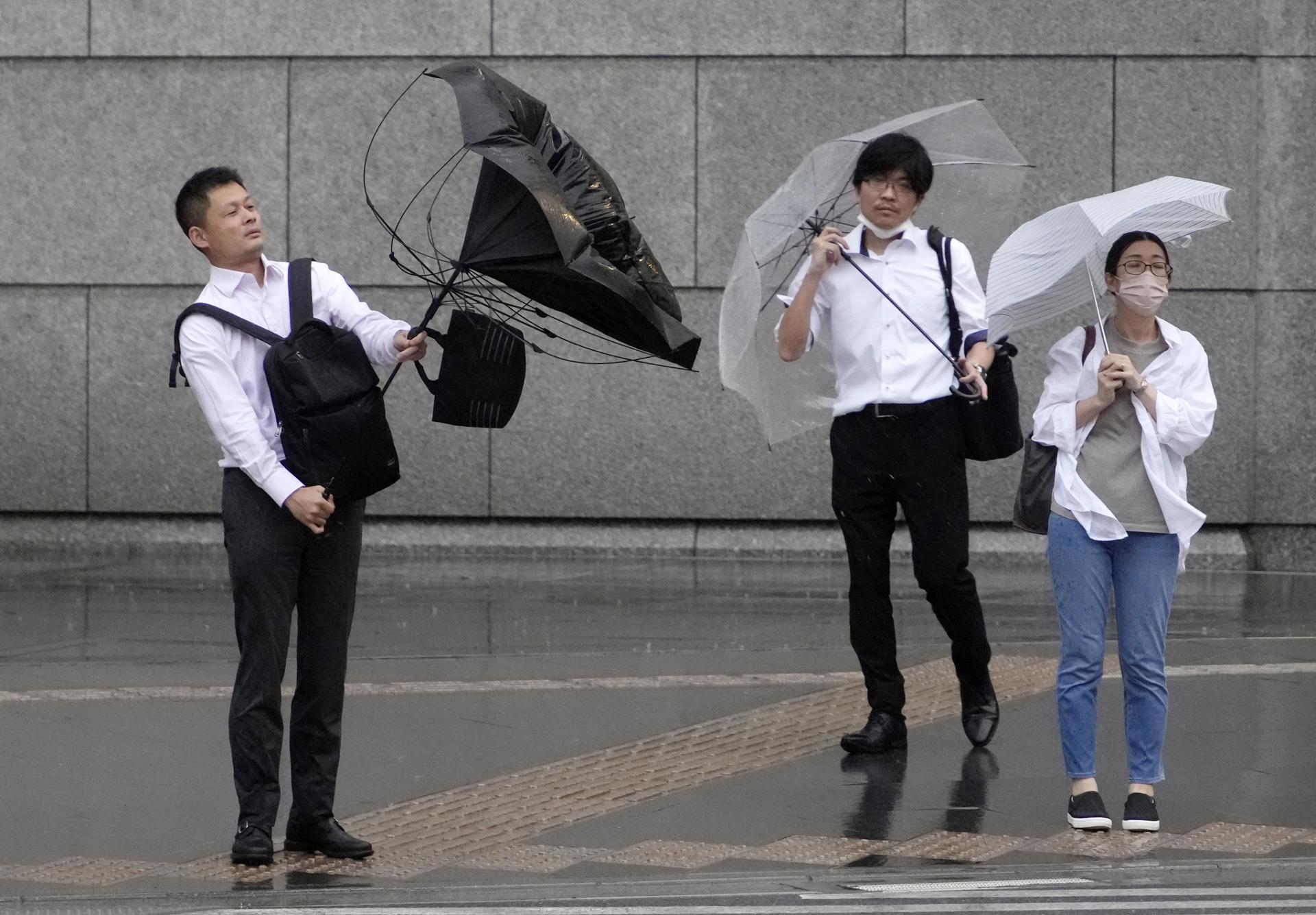 Personas peleando contra el viento tras lluvias de Japón