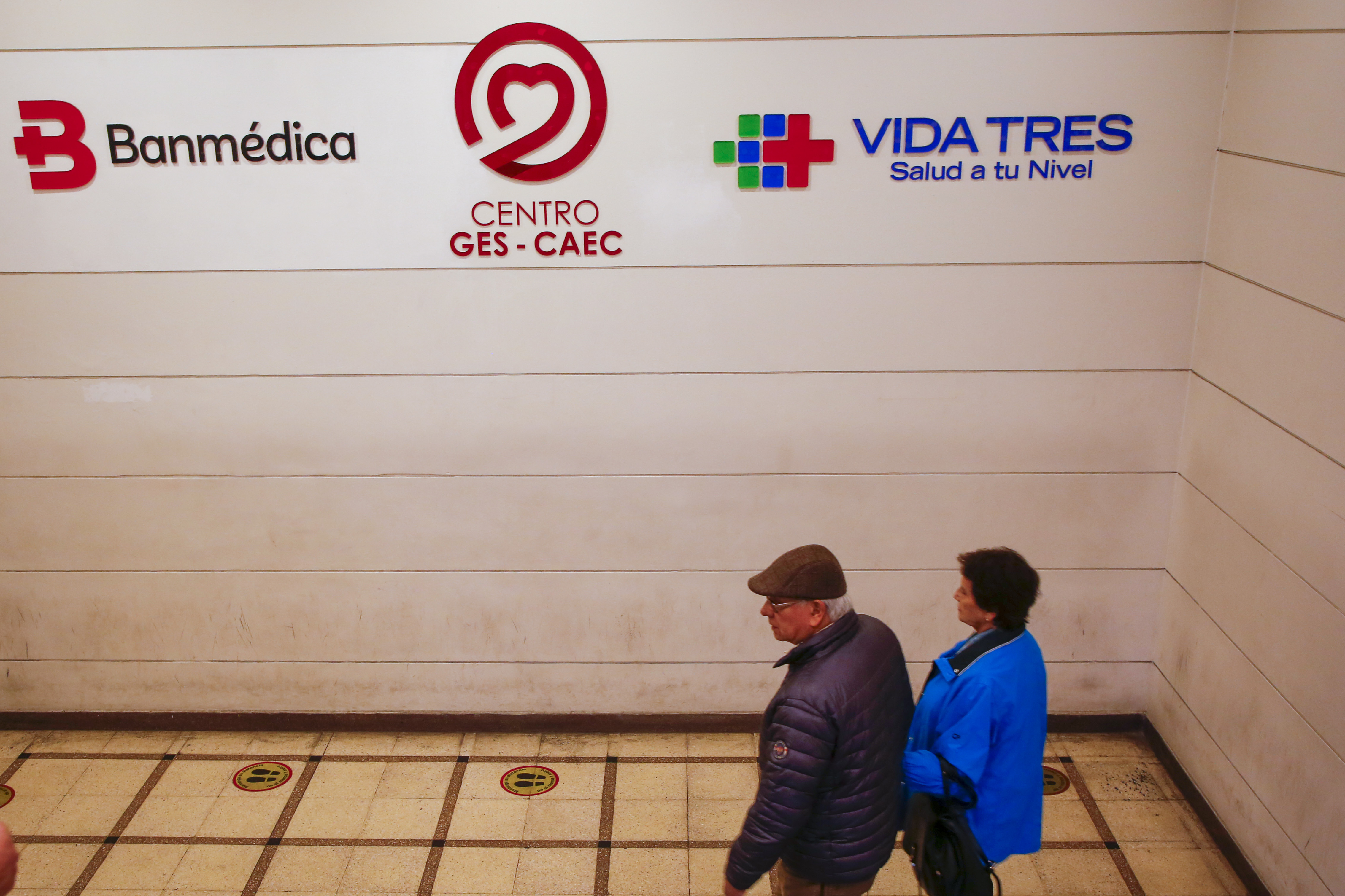 Adultos mayores caminando bajo logos de Isapres.