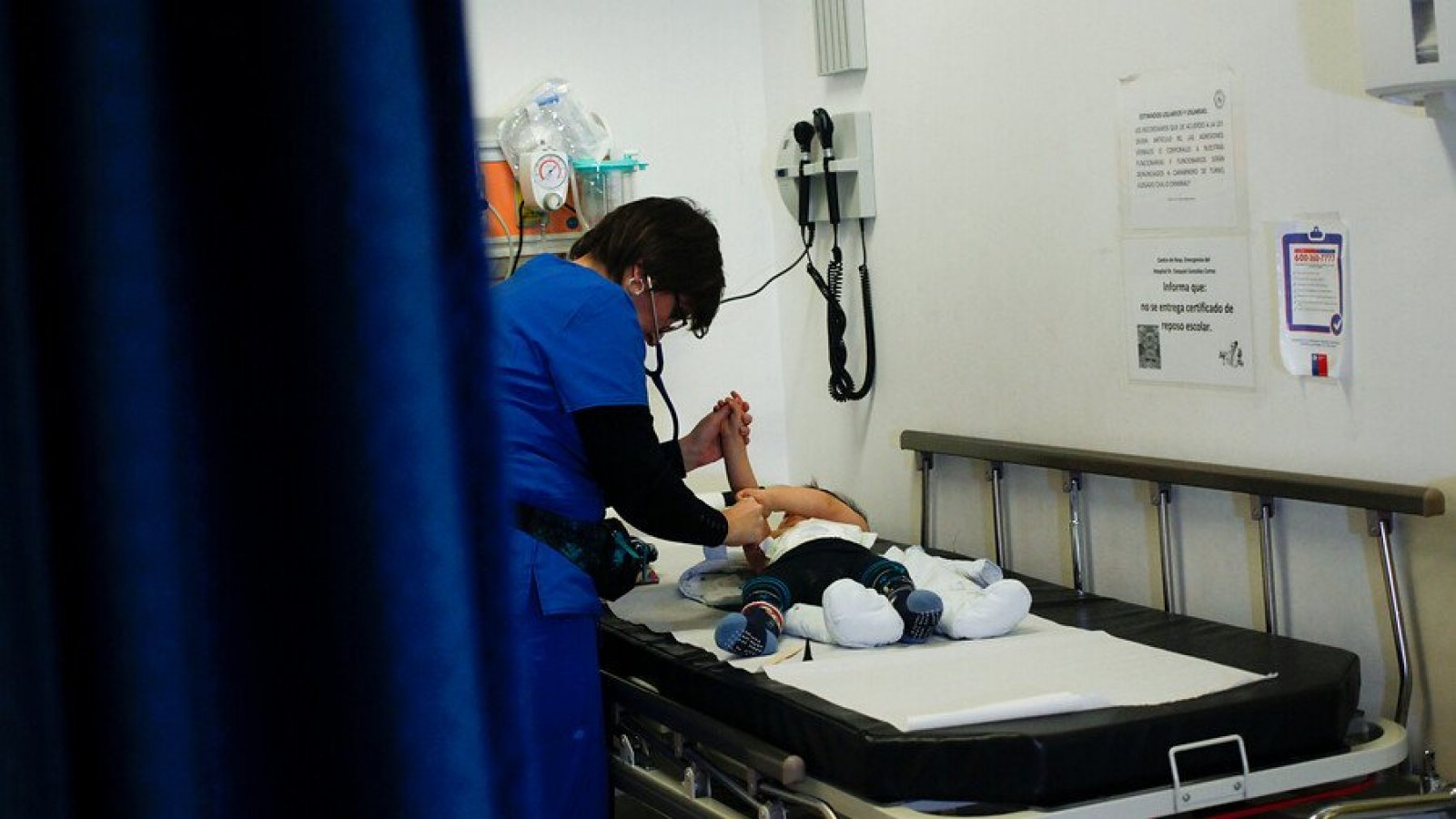 Enfermera atendiendo a un bebé con virus sincicial en una camilla de hospital.