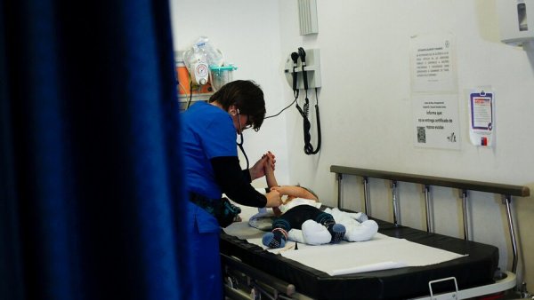 Enfermera atendiendo a un bebé con virus sincicial en una camilla de hospital.