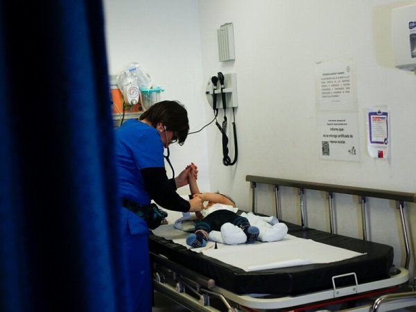 Enfermera atendiendo a un bebé con virus sincicial en una camilla de hospital.