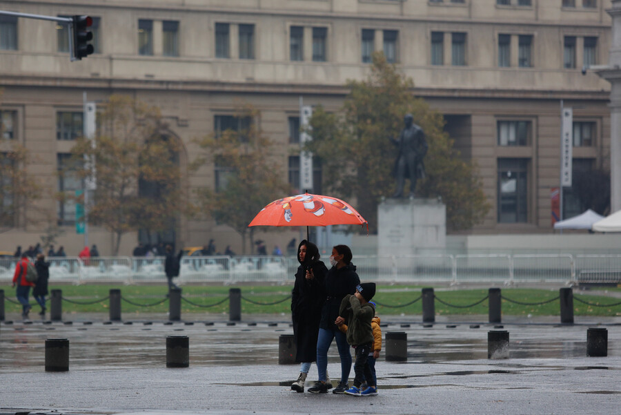 Personas caminando bajo la lluvia en Santiago.