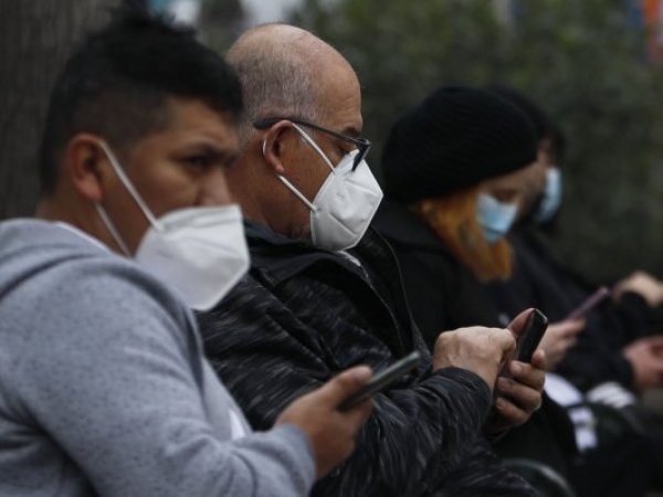 Personas con mascarilla revisando su celular.