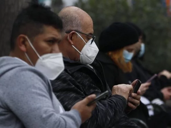 Personas con mascarilla revisando su celular.