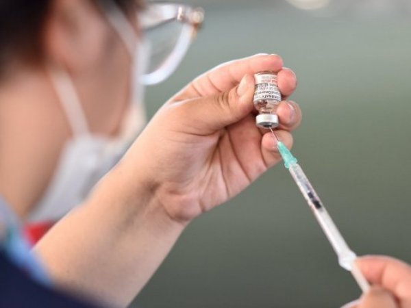 Enfermera llenando una aguja con líquido.