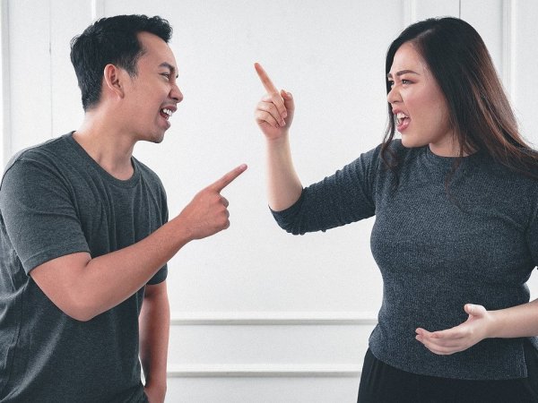 Pareja discutiendo con sus manos arriba.