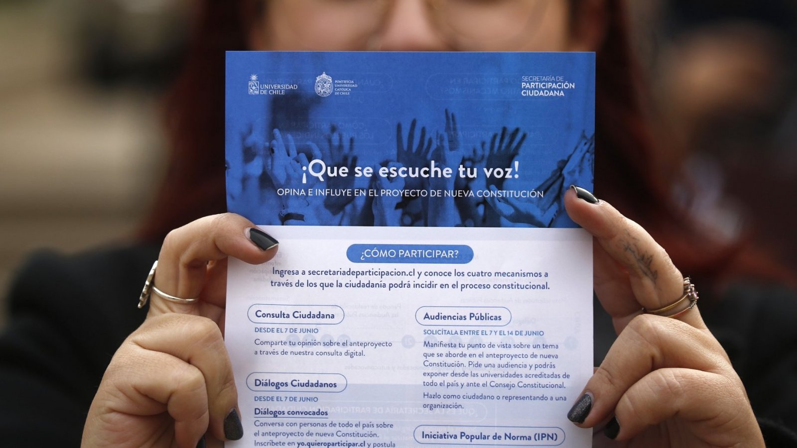 Mujer sujetando folleto con los mecanismos de participación del proceso constituyente
