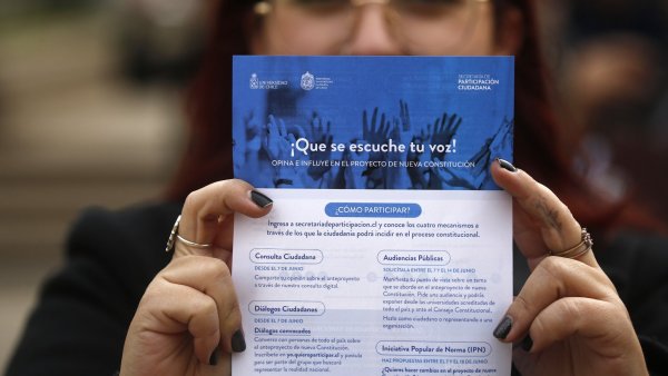 Mujer sujetando folleto con los mecanismos de participación del proceso constituyente