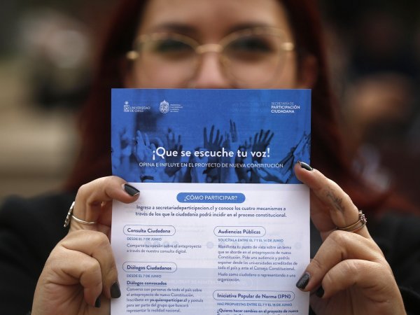 Mujer sujetando folleto con los mecanismos de participación del proceso constituyente