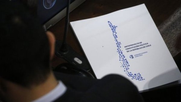 Consejero con un libro del anteproyecto constitucional al lado.