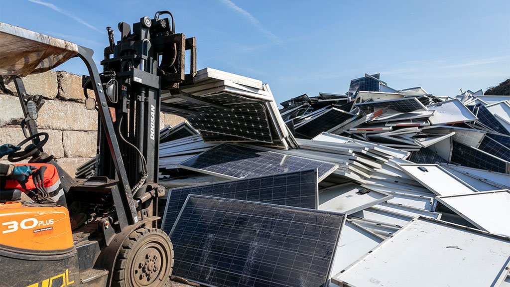 Una excavadora ayudando a remover páneles solares usados.