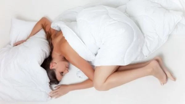 Mujer durmiendo encima de un colchón blanco.