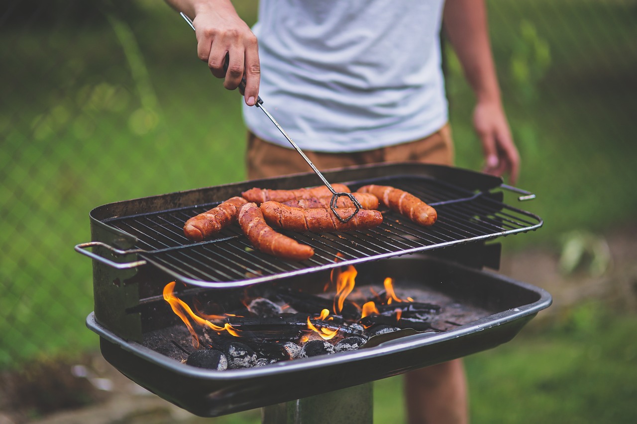 Joven preparando un asado de salchichas.