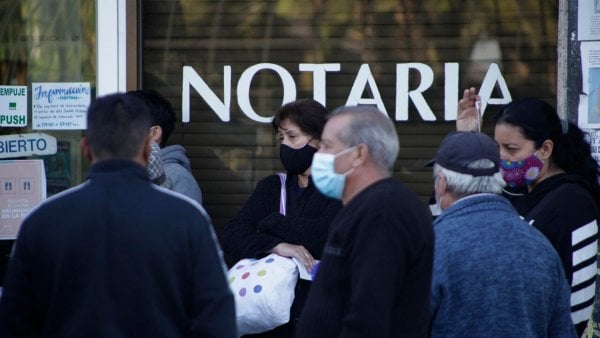 Personas haciendo fila fuera de una notaría.