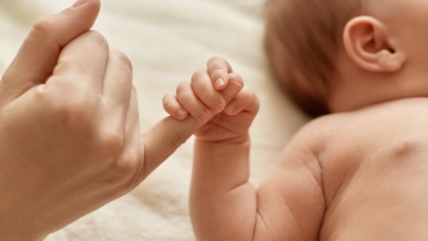 Mano de un bebé agarrando el dedo de un adulto.