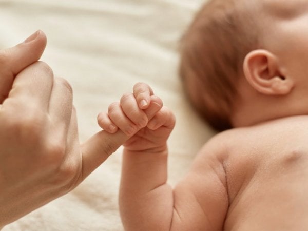 Mano de un bebé agarrando el dedo de un adulto.