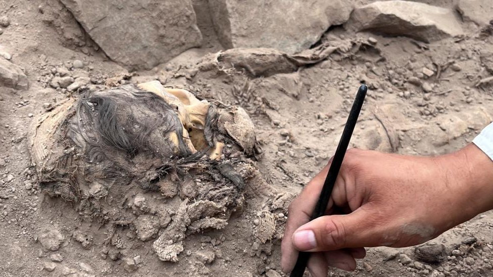 Un arqueólogo trabajando en el sitio de excavación de un entierro prehispánico junto a una momia que se cree que es de la cultura Manchay, que habitó en los valles de Lima entre 1500 y 1000 a. C., en Lima, Perú, el 14 de junio de 2023.