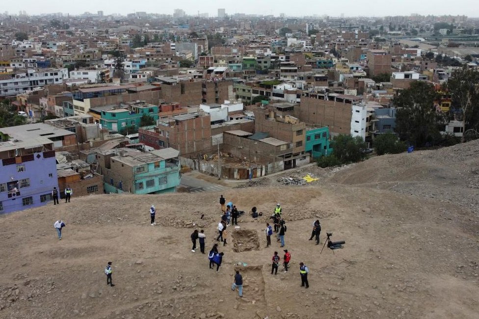 Un grupo de gente cerca del sitio de excavación de un entierro prehispánico con una momia, que se cree que es de la cultura Manchay que habitó en los valles de Lima entre 1500 y 1000 a. C., en Lima, Perú, el 14 de junio de 2023.