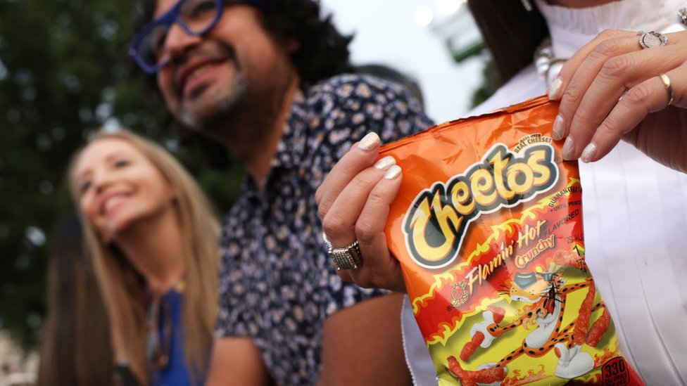 Una persona con una bolsa de Cheetos Flamin' Hot en la Casa Blanca