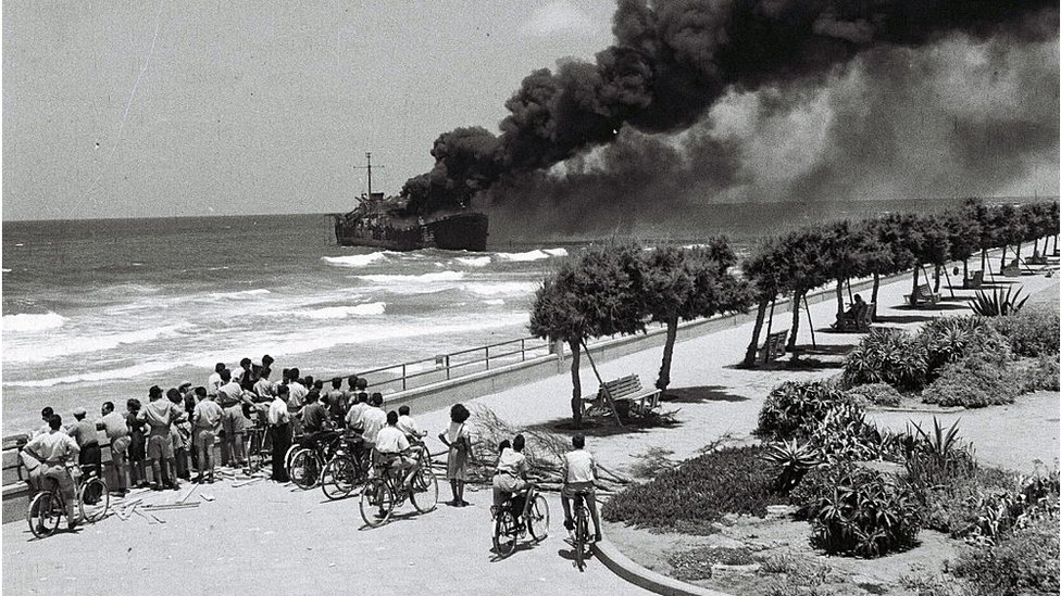 Personas observan el incendio en el barco Altalena.