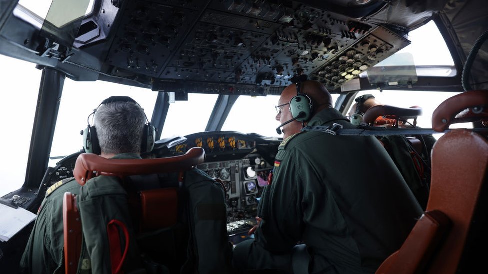 Dos tripulantes de un avión miran al océano