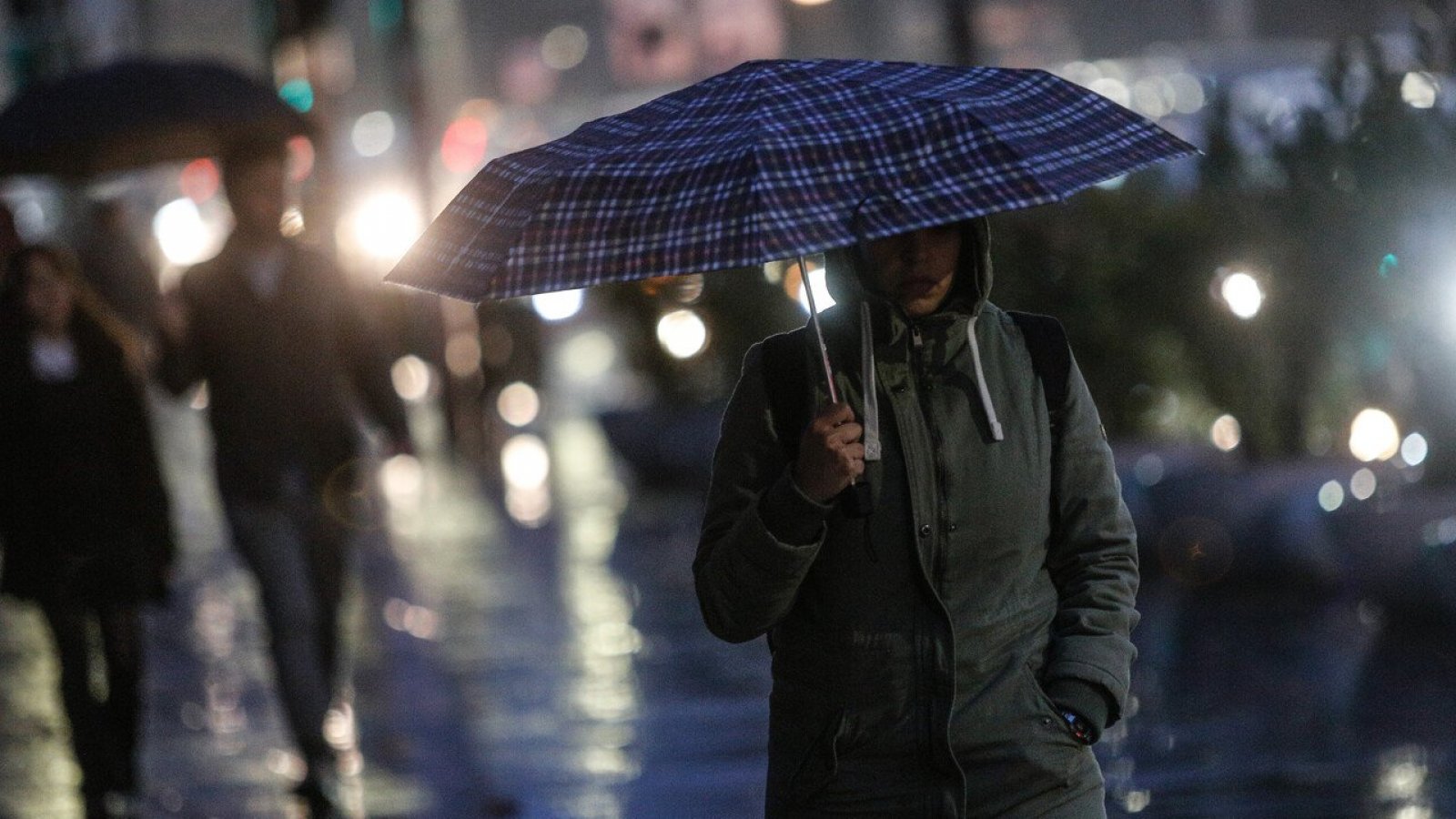Persona con paraguas caminando bajo la lluvia en Santiago.