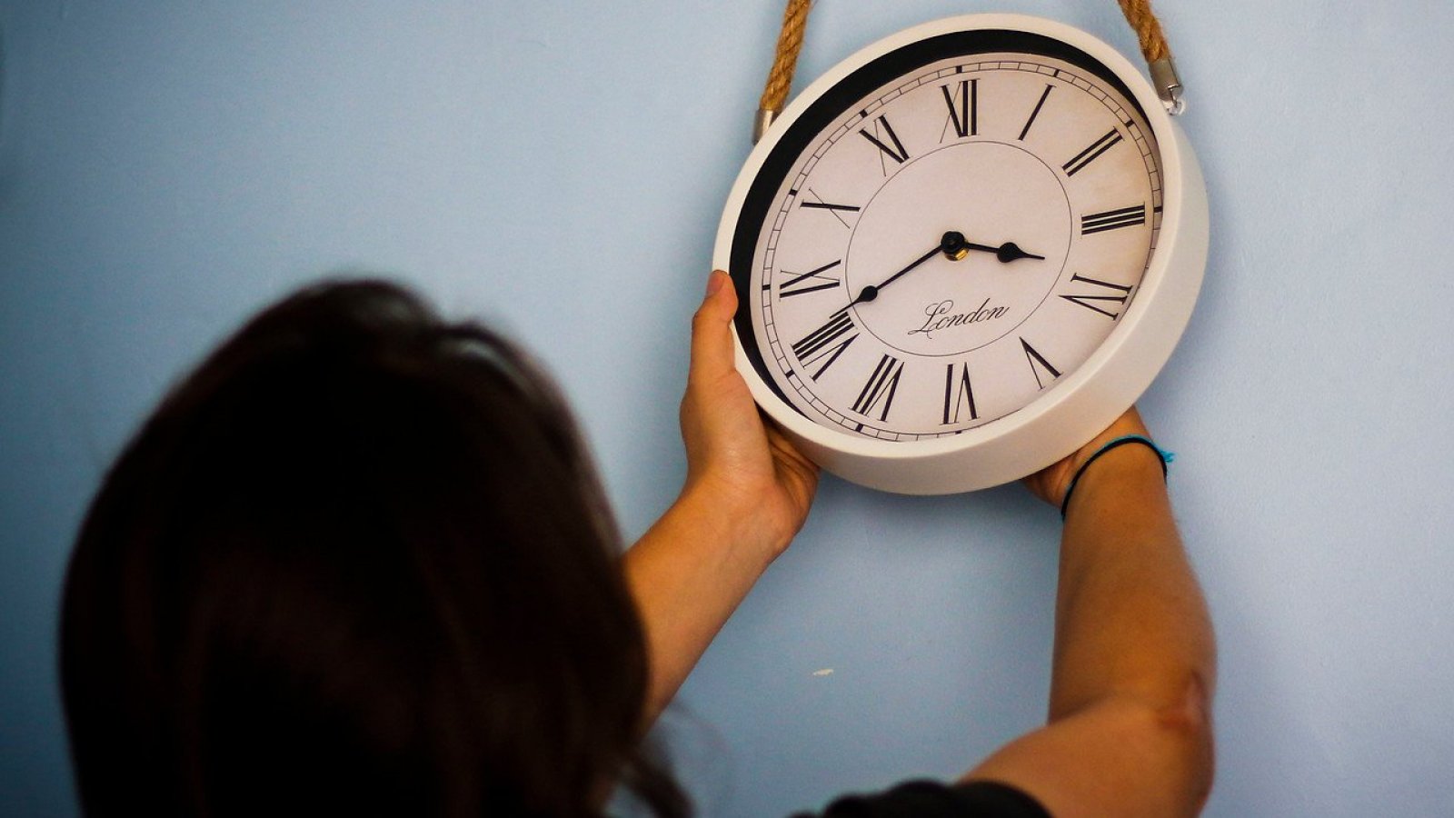 Mujer cambiando la hora de un reloj.