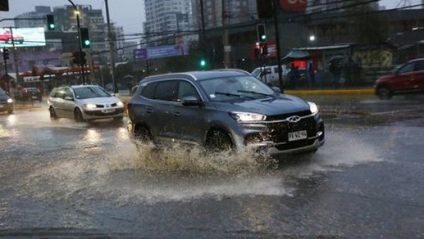 Auto pasando por calle anegada.