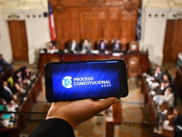 Teléfono con logo del proceso constitucional en sala del Consejo Constitucional.