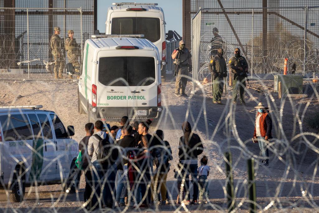 La policía junto a inmigrantes que intentan cruzar la frontera entre Estados Unidos y México en Texas sin documentos, incluidos niños