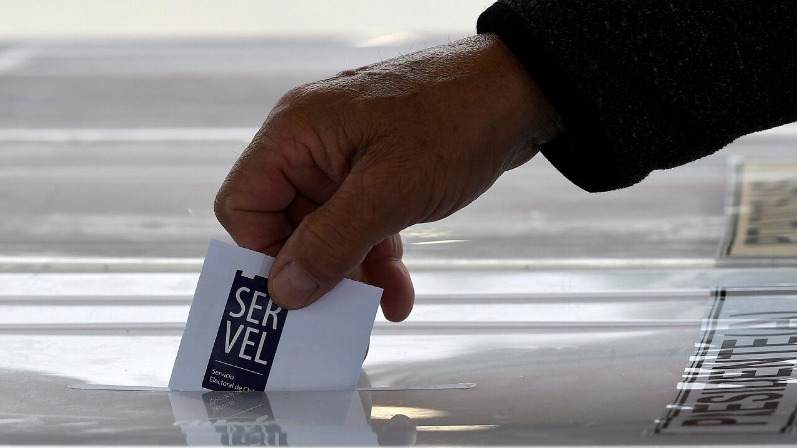 Mano ingresando voto en una urna electoral del Servel.