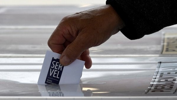 Mano ingresando voto en una urna electoral del Servel.