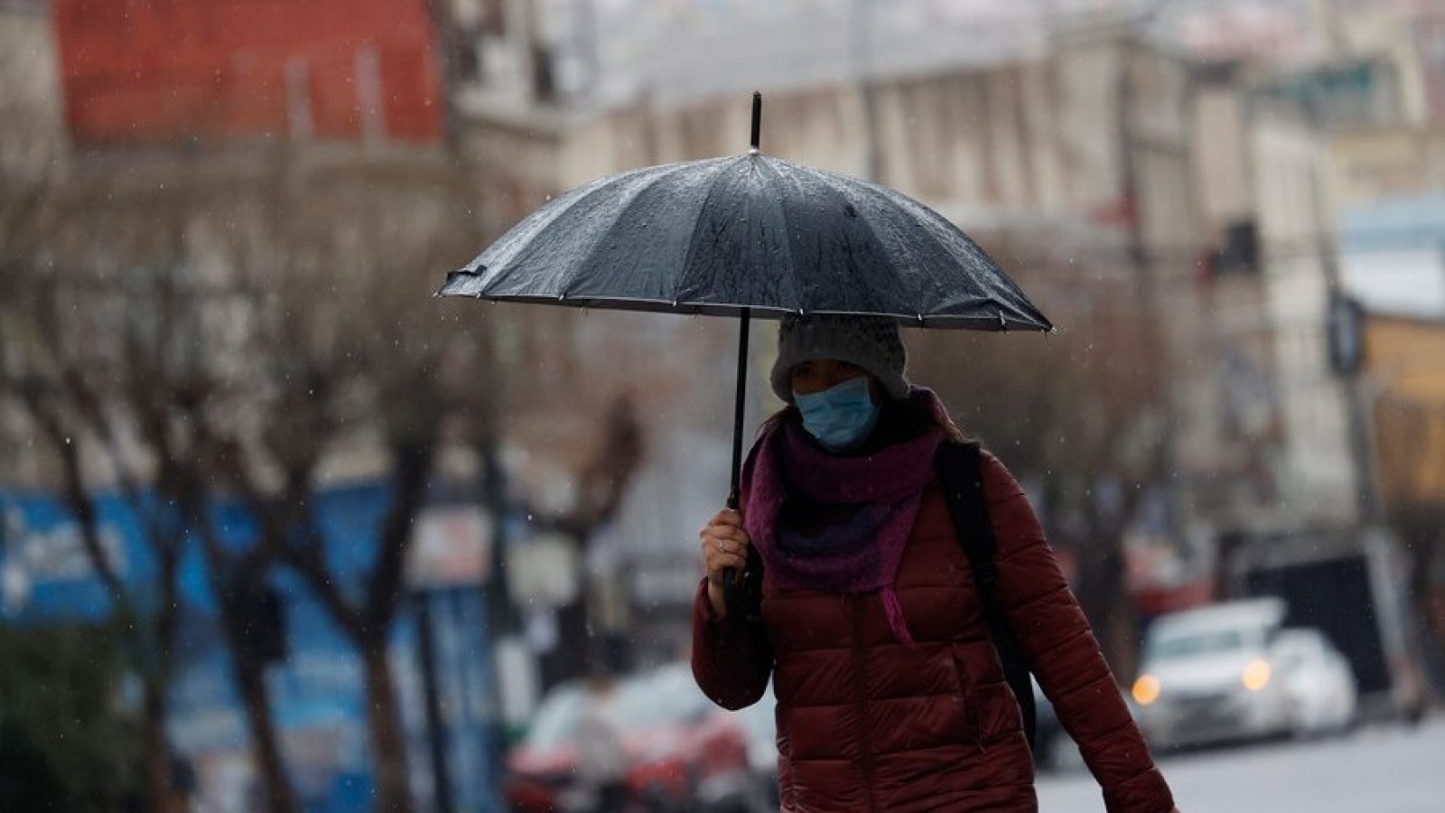 Mujer caminando bajo la lluvia con paraguas.