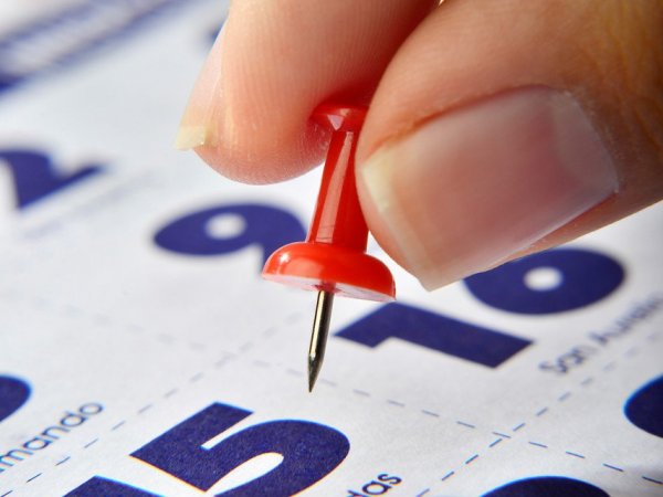 Mano marcando un feriado en el calendario.