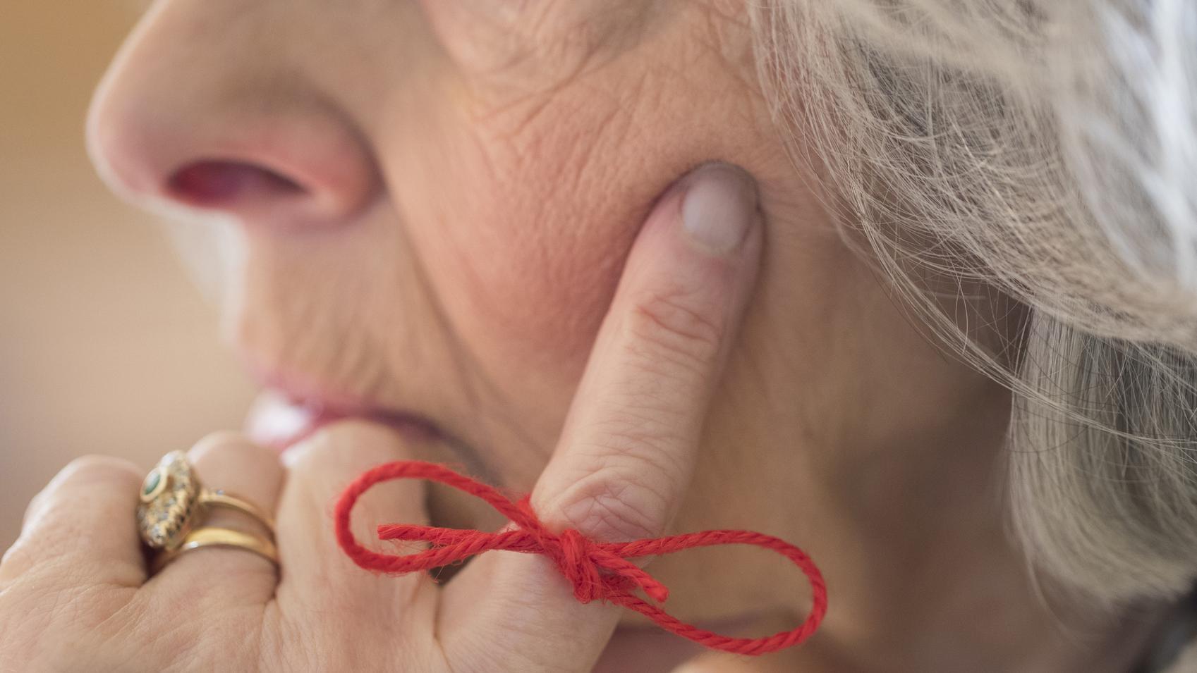 Una mujer anciana que padece alzhémier con un cordel anudado en su dedo como recordatoreio de algo